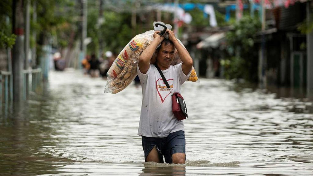 A-vendor-carries-food-products-as-he-wades-through-a-flooded-street-following-heavy-rains-brought-by-tropical-storm-Nalgae