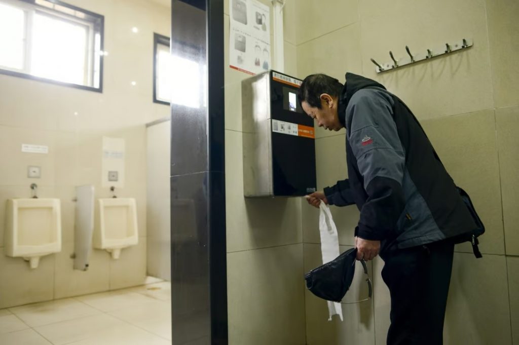 A man uses an automatic toilet paper dispenser that uses facial recognition technology at a public toilet at the Temple of Heaven in Beijing on March 21, 2017 Photo AFP